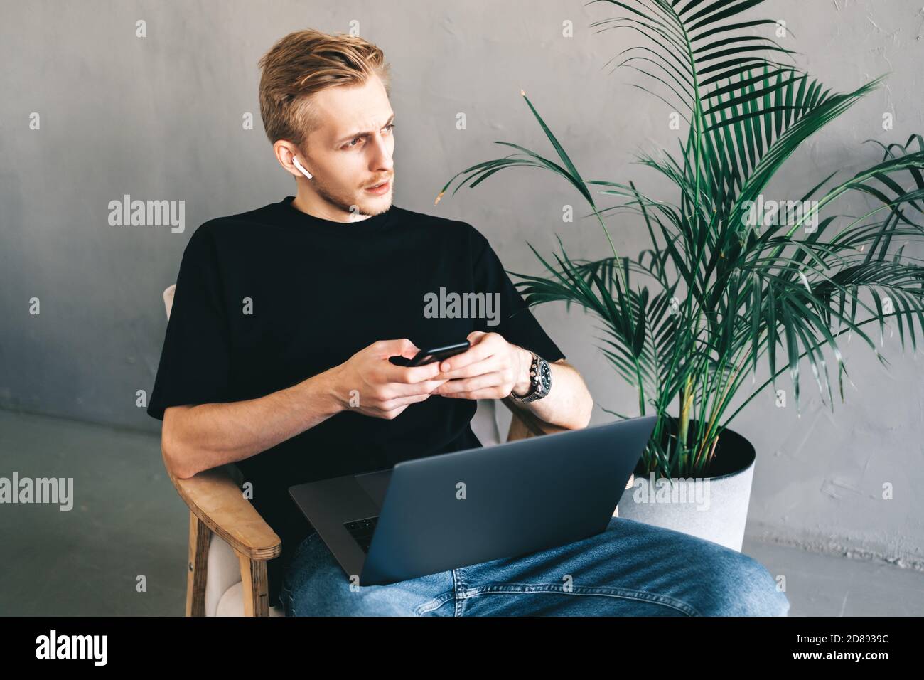 Mman mobile developer in earphones using smartphone, testing application Stock Photo