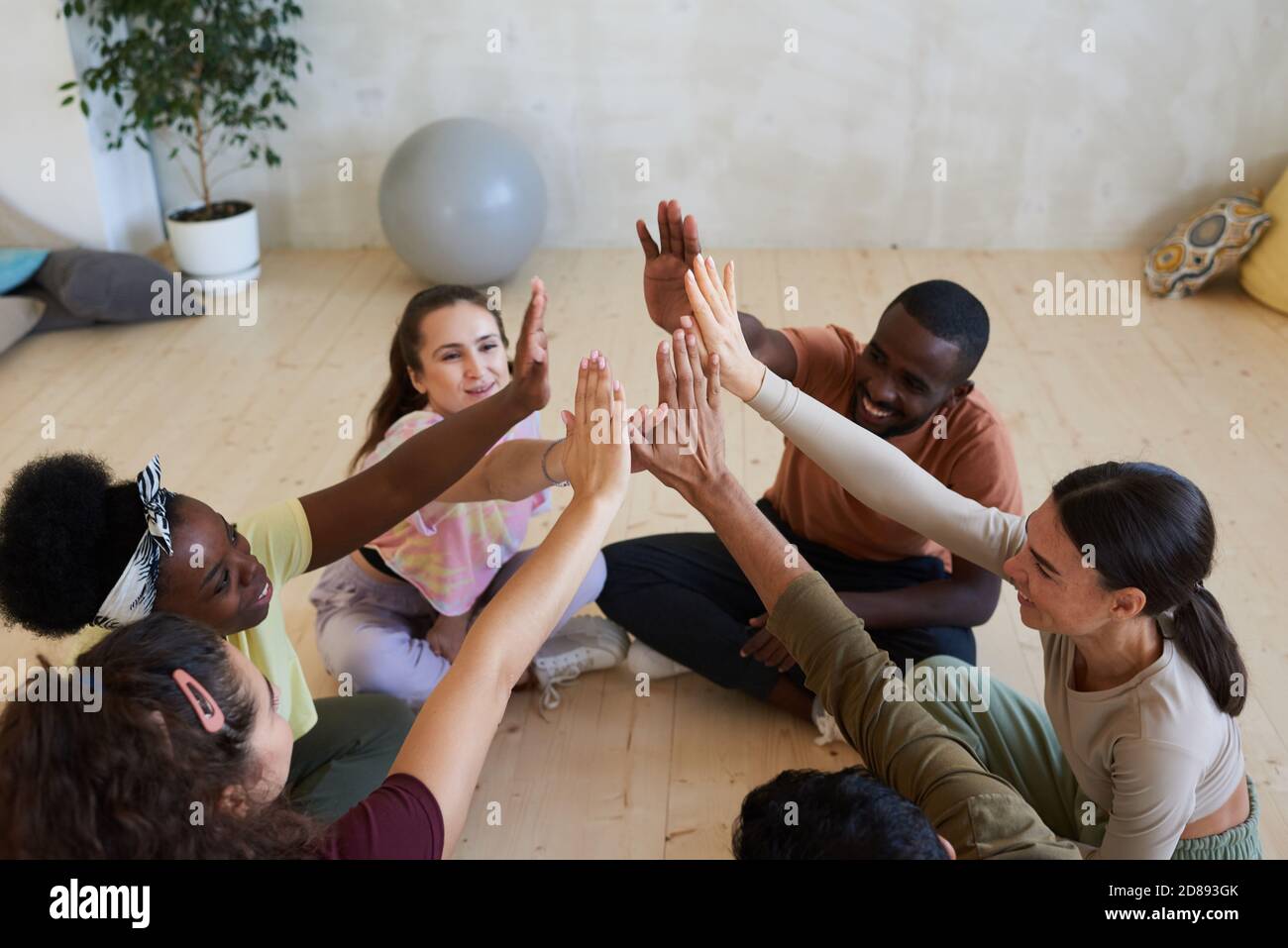 Group of people sitting on the floor and giving high five during therapy class Stock Photo