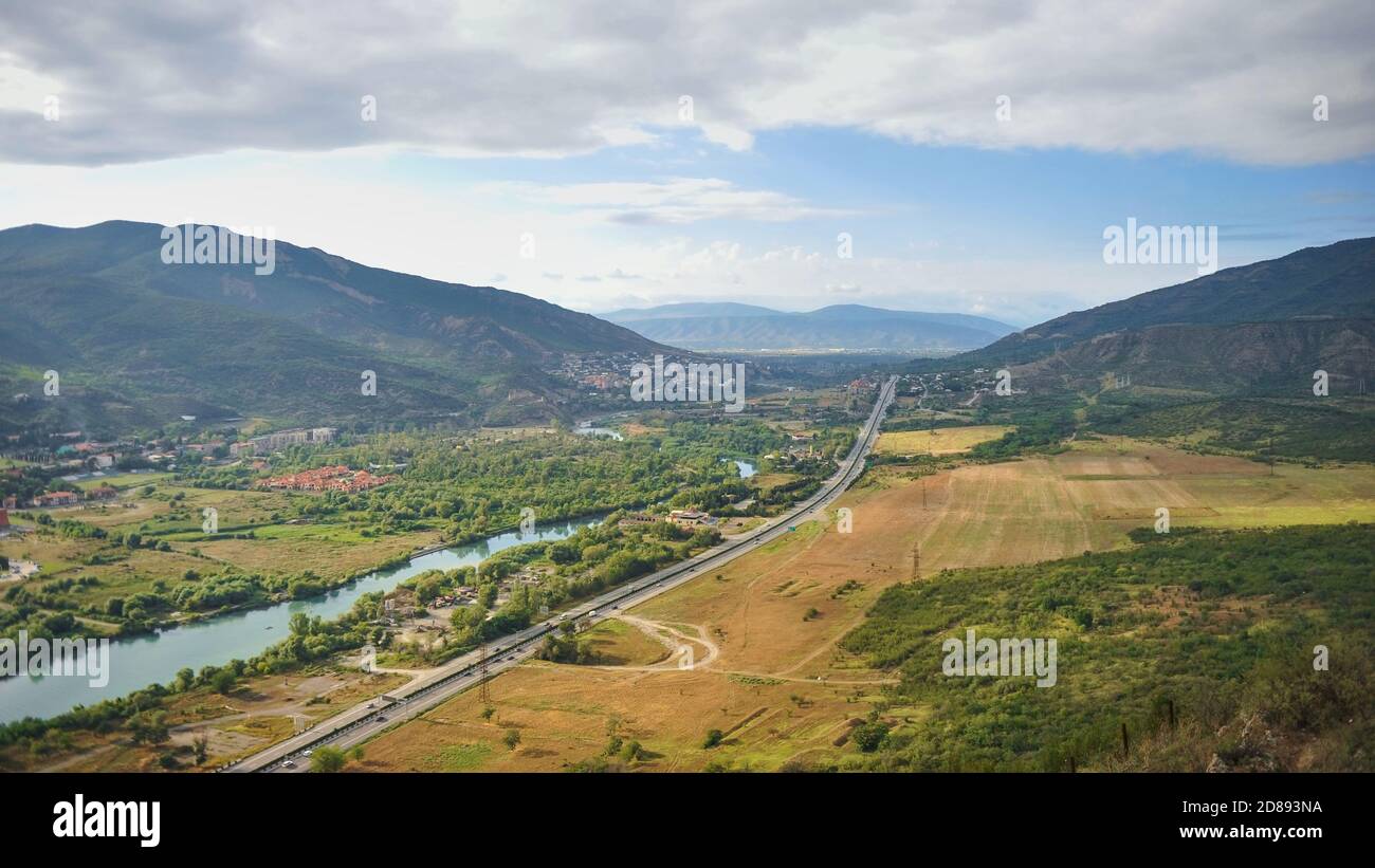 View to road crossing valley of Aragvi river, Tbilisi suburban villages, rich farmland in Caucasus mountains,Georgia. Stock Photo