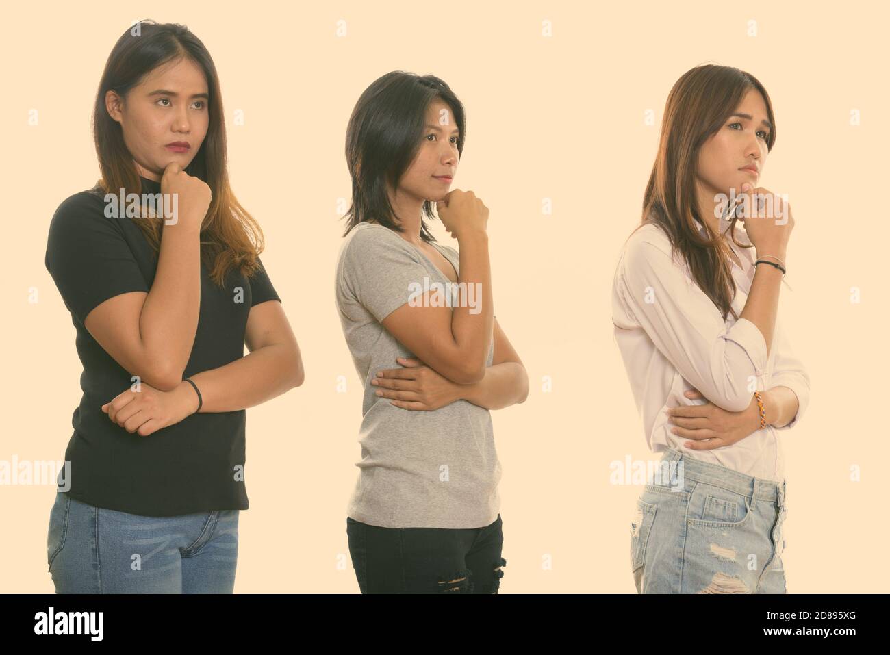 Studio shot of three young Asian woman friends thinking while looking at distance Stock Photo