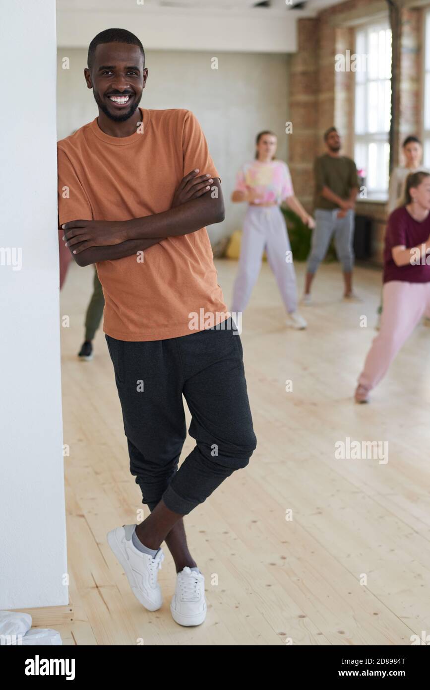 Portrait of African young dancer smiling at camera with people exercising in the background in dance studio Stock Photo