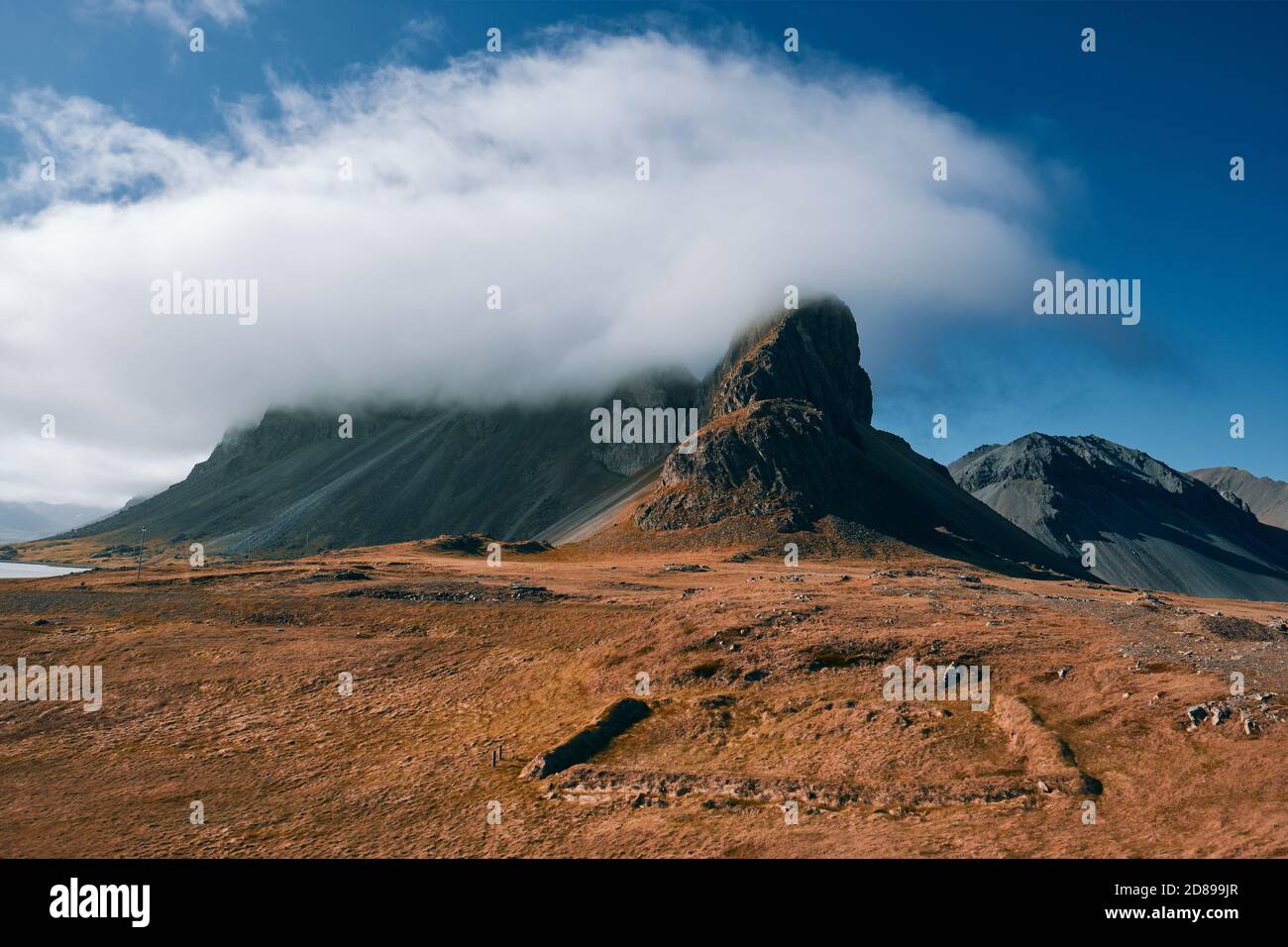 A minimal low cloud formation over a Iceland mountain peaks landscape - low cloud mountain tops - mountain cloud formation - Eystrahorn Iceland Stock Photo