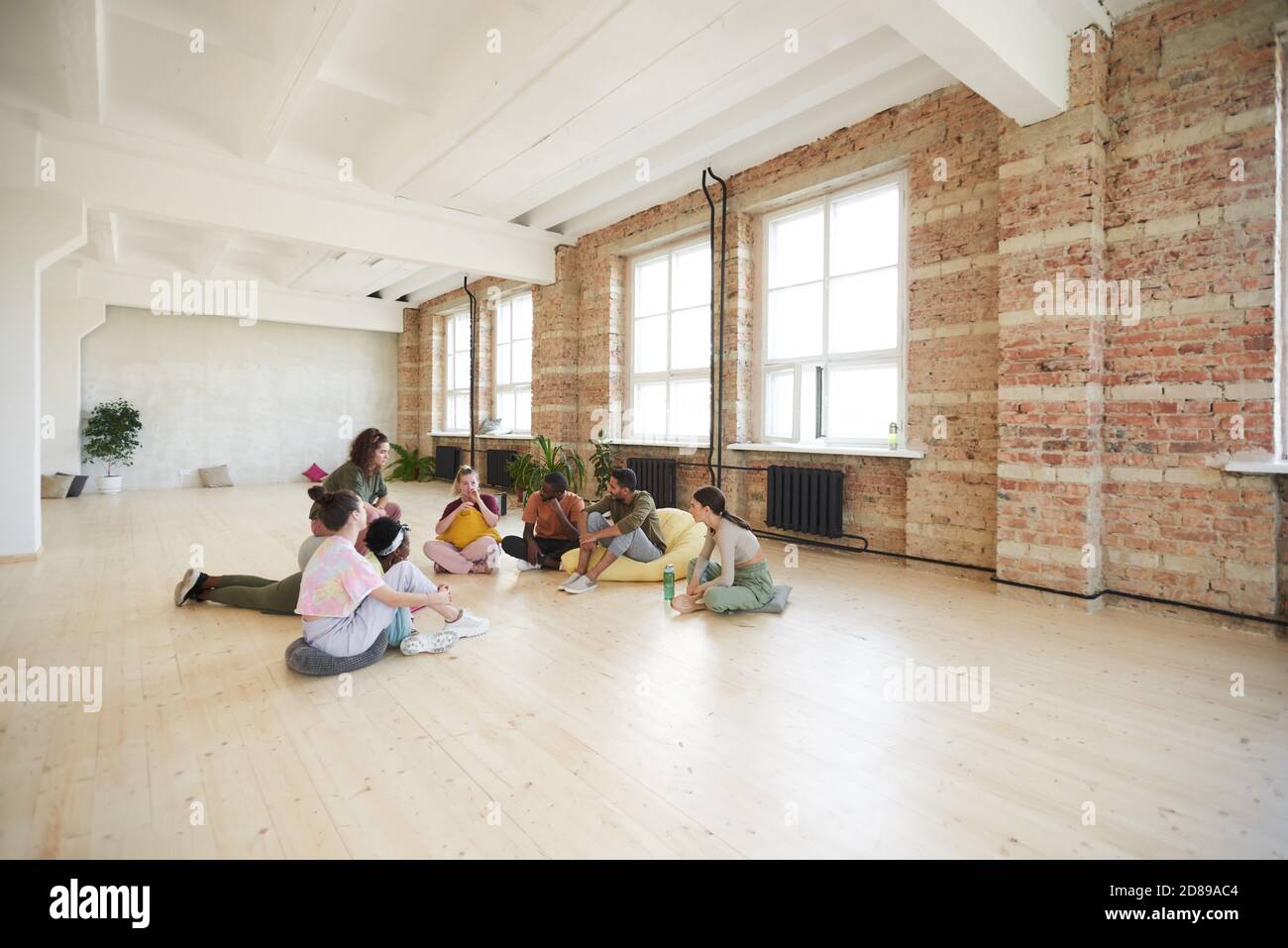Group of young dancers sitting on the floor resting and talking in