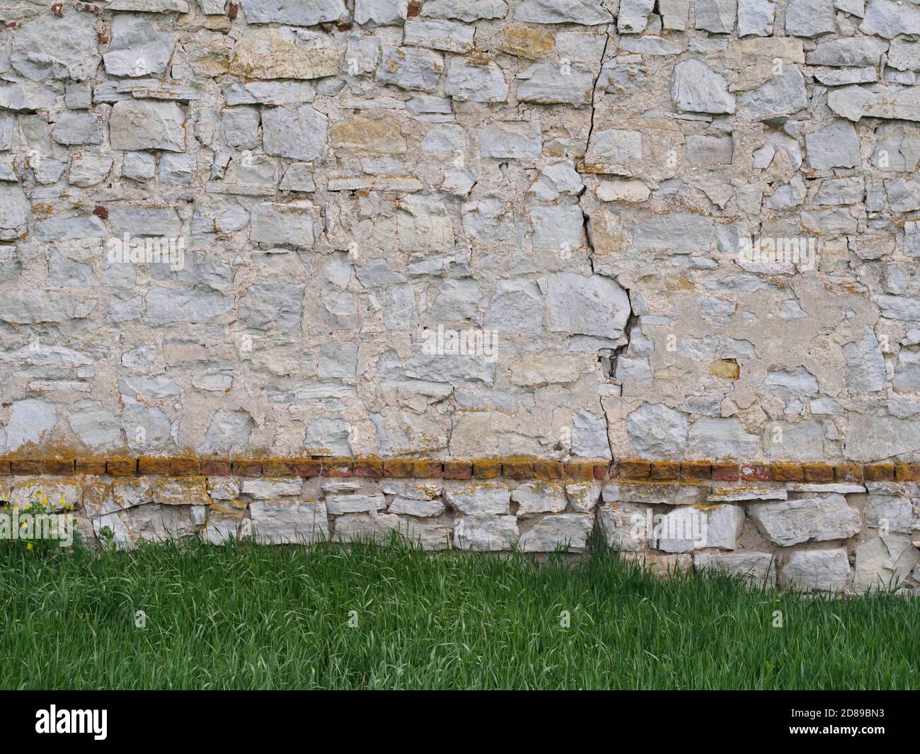 Stone wall on the grass meadow background Stock Photo - Alamy