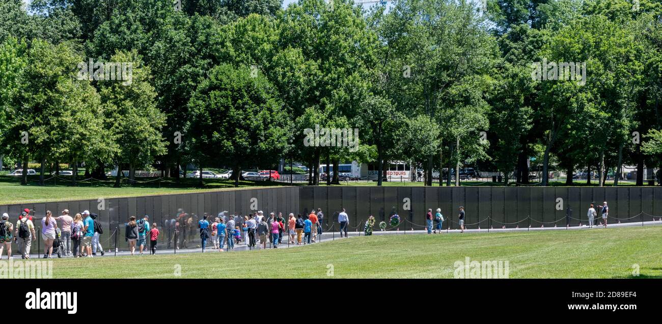 Friends and relatives search on the polished black granite walls of the Vietnam Veterans Memorial for the names of loved ones lost in the war. Stock Photo