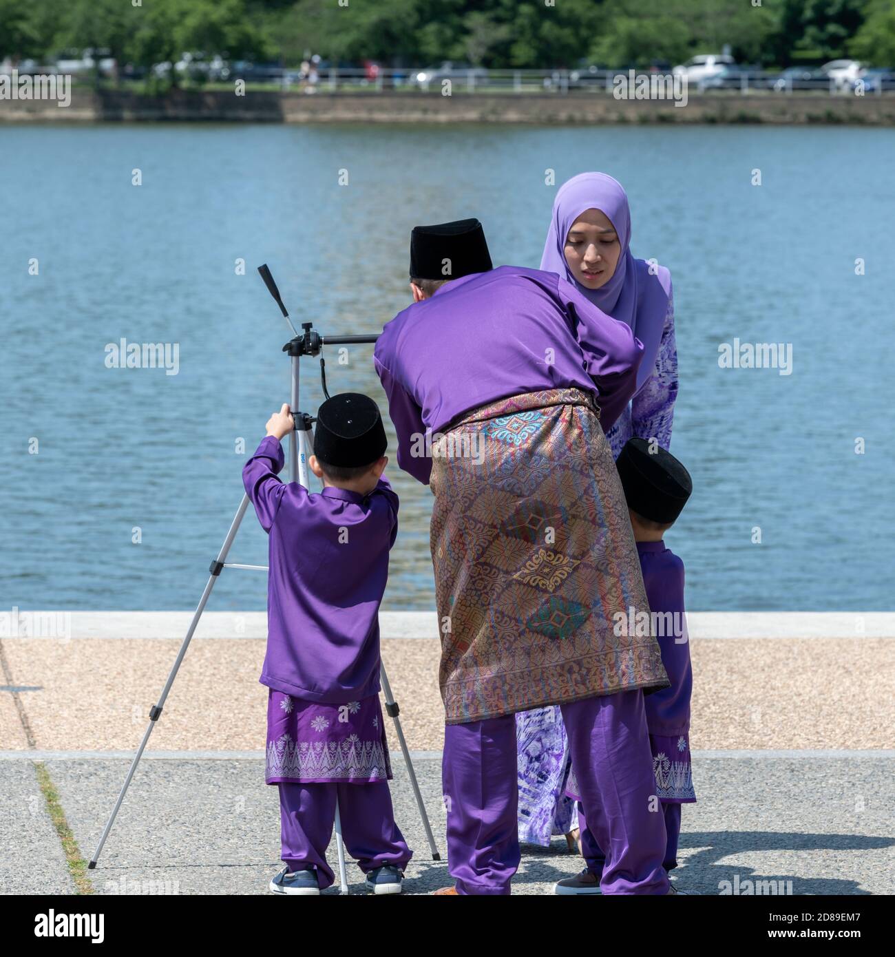 A colourful Asian family in tradtional clothes sets up for a family photograph by the Potomac River Tidal Basin. Stock Photo