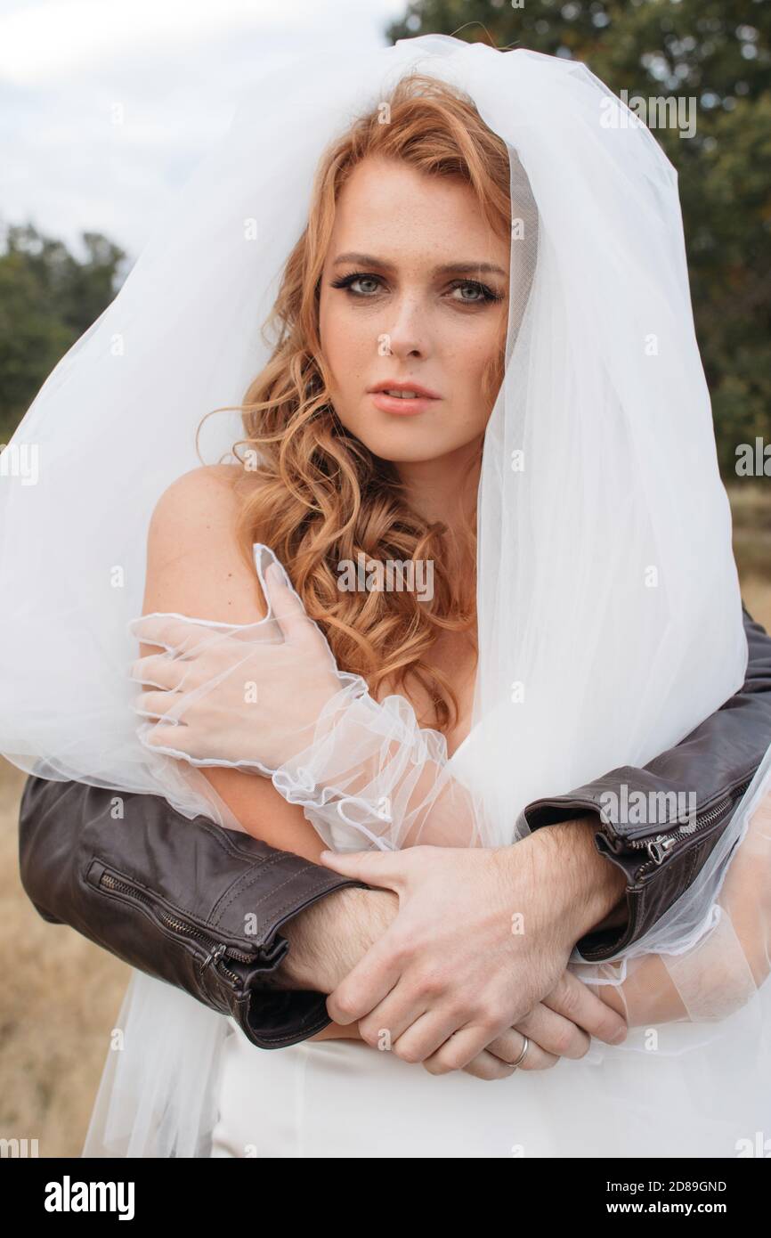 Man in a leather jacked with his arms around a bride Stock Photo