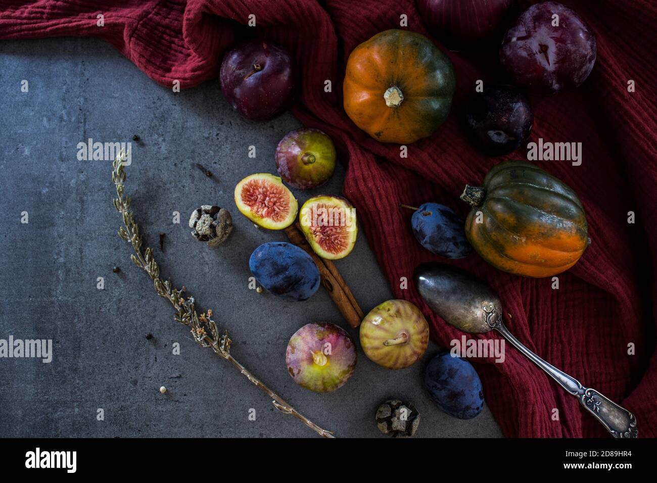 Fresh fruits and vegetables on a table. Top view photo of grapes, pumpkins, plums and figs. Grey textured background. Autumn still life. Stock Photo