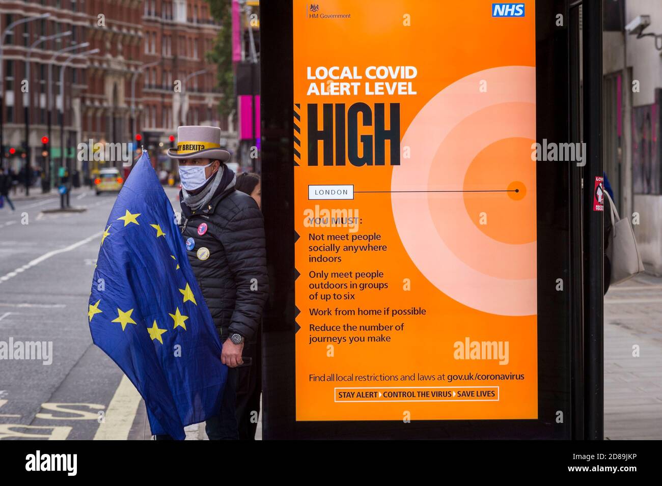 London, UK.  28 October 2020.  Steve Bray, an anti-Brexit protester from SODEM next to a Covid-19 alert related sign at a bus stop outside the Department for Business, Energy & Industrial Strategy in Westminster.  Michel Barnier, the European Commission's Head of Task Force for Relations with the United Kingdom, is attending meetings inside.  Credit: Stephen Chung / Alamy Live News Stock Photo