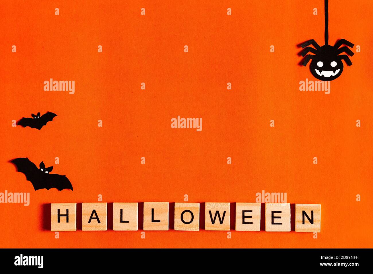 Halloween lettering on orange background with black paper silhouettes, bats, pumpkin, spider. The Concept Of Halloween. the view from the top Stock Photo