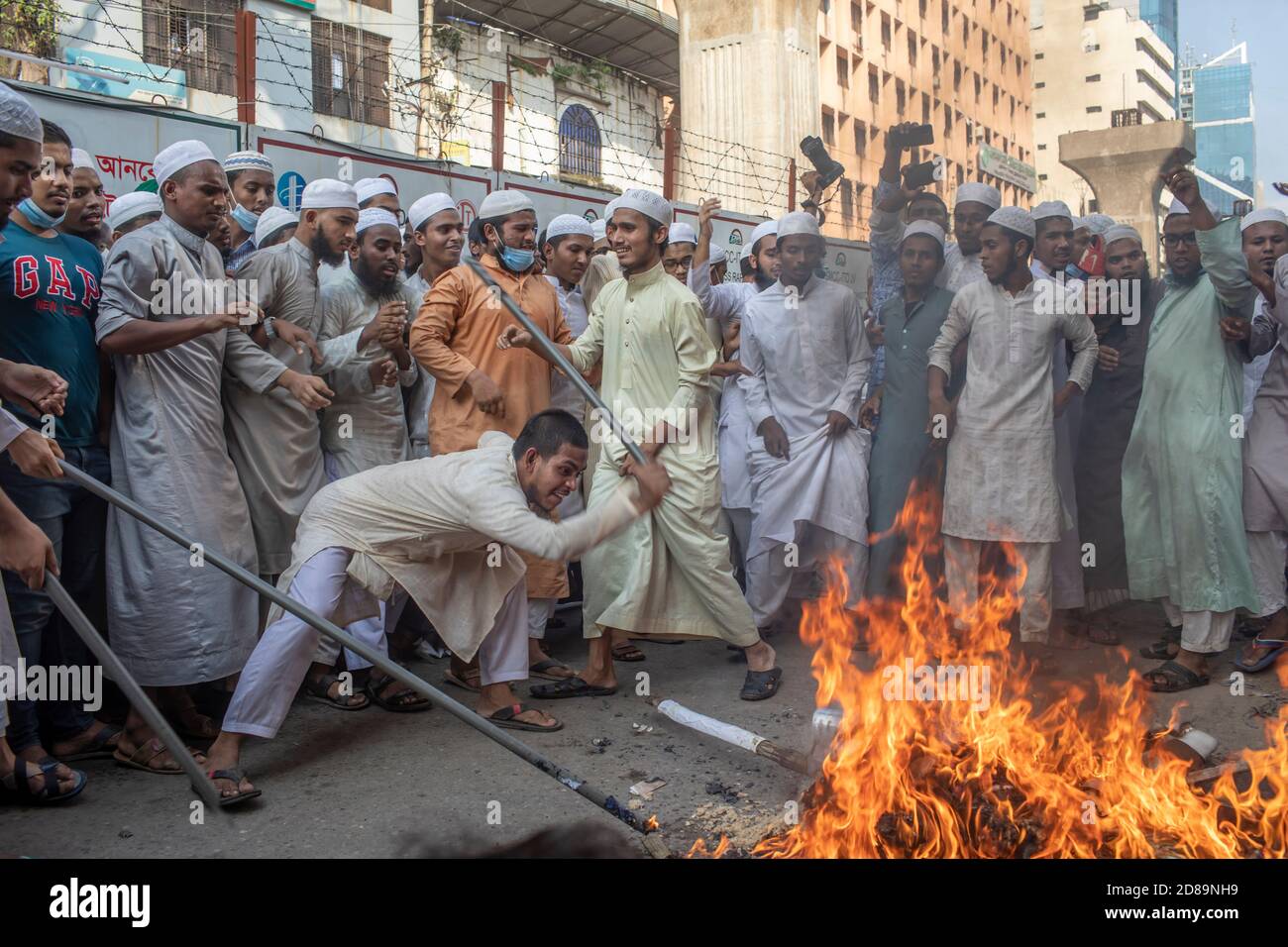 Leaders and activists of the Islami Oikya Jote, an Islamist political party, burn an effigy of French president Emmanuel Macron during the protest against French President in Dhaka.Thousands of Muslim protesters hold a march calling for the boycott of French products and denouncing French president Emmanuel Macron for his remarks ‘not to give up cartoons depicting Prophet Mohammed'. Macron's remarks came in response to the beheading of a teacher, Samuel Paty, outside his school in a suburb outside Paris earlier this month, after he had shown cartoons of the Prophet Mohammed during a class he w Stock Photo