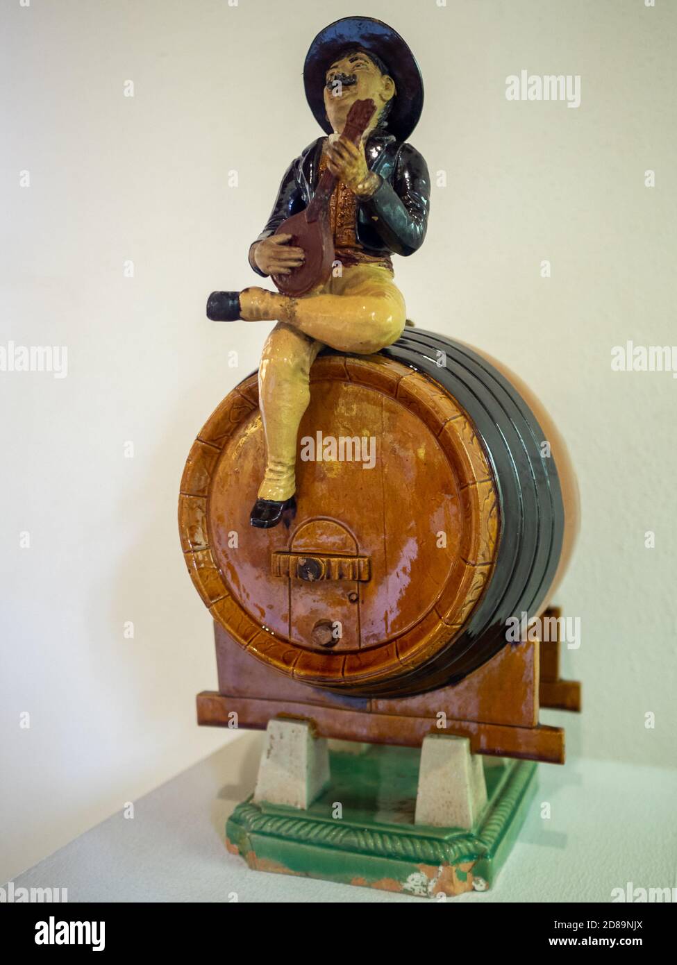 Man playing Portuguese guitar seated in a wine barrel made in ceramics by Rafael Bordalo Pinheiro Stock Photo