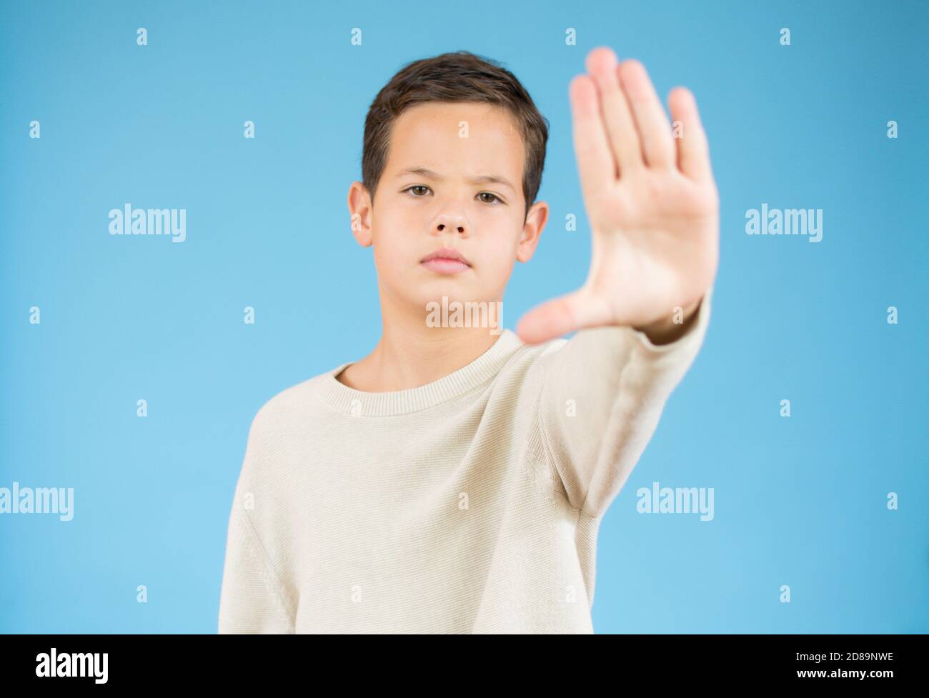 Boy making stop gesture with his palm on blue background. Body language ...