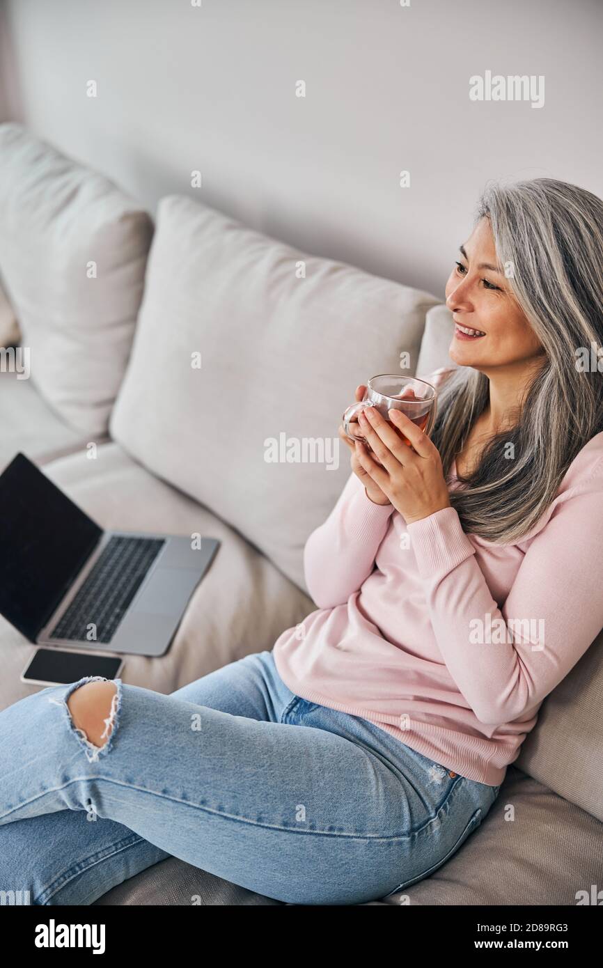 Charming woman sitting on sofa and drinking tea at home Stock Photo - Alamy