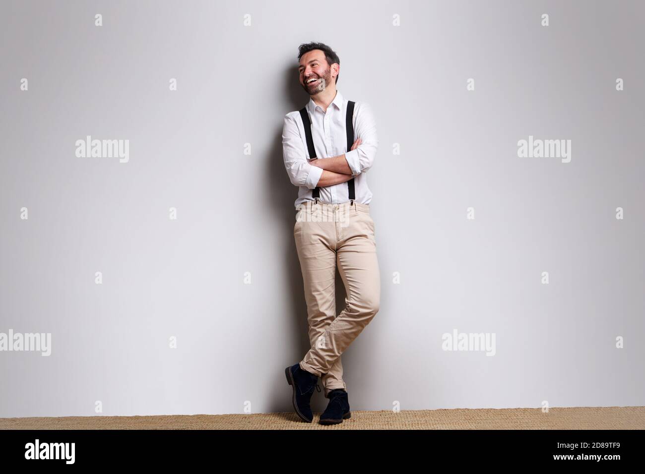 Full length portrait of happy man with suspenders laughing against gray background Stock Photo