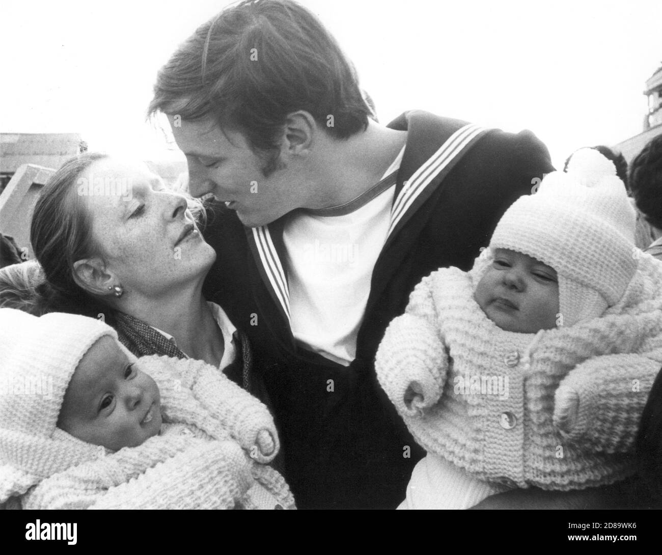 SEEING HIS TWIN DAUGHTERS FOR THE FIRST TIME IS NEWLY PROMOTED PETTY OFFICER ALAN DENHAM. HE WAS GREETED BY THE TWINS CLAIRE AND DONNA AND HIS WIFE CHERYL (22) WHEN HMS ILLUSTRIOUS ARRIVED BACK IN PORTSMOUTH FROM THE FALKLANDS. . PORTSMOUTH 1982   SEING HIS TWIN DAUGHTERS CLAIRE AND DONNA FOR THE FIRST TIME IS NEWLY PROMOTED PETTY OFFICER ALAN DENHAM. HE WAS GREETED BY THE TWINS AND WIFE CHERYL WHEN HMS ILLUSTRIOUS DOCKED AT PORTSMOUTH AFTER HER TOUR OF DUTY IN 1982, Stock Photo