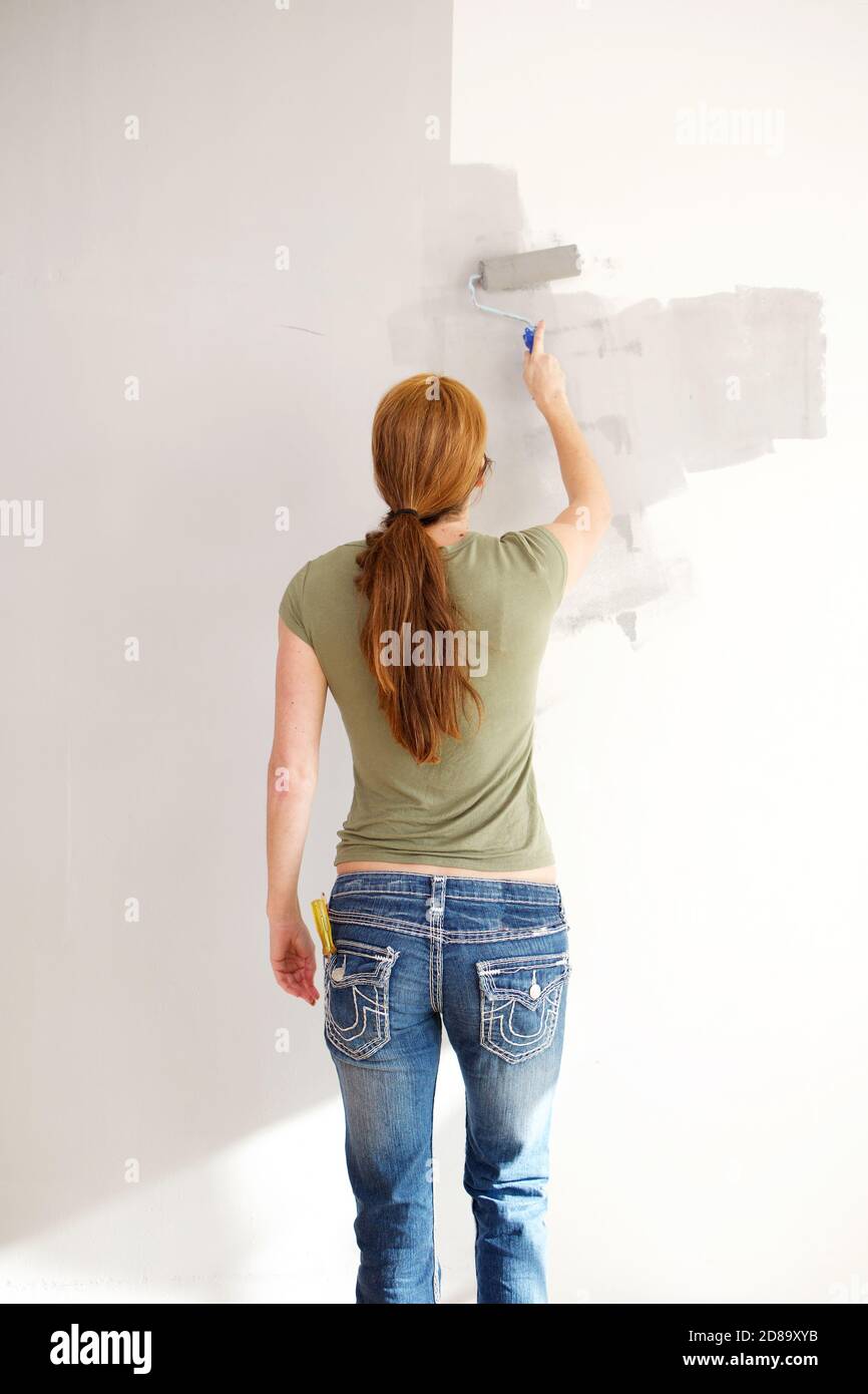 Portrait from behind mature woman applying paint on wall with paint