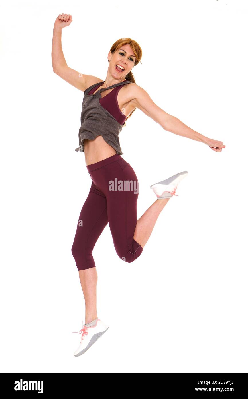 Full body portrait of attractive older woman in sportswear jumping over white background Stock Photo