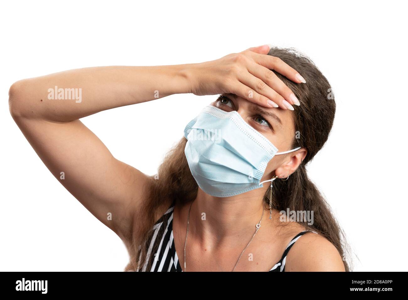 Adult woman touching forehead as high fever body temperature sars covid19 influenza cold flu symptom concept with medical mask covering nose and mouth Stock Photo