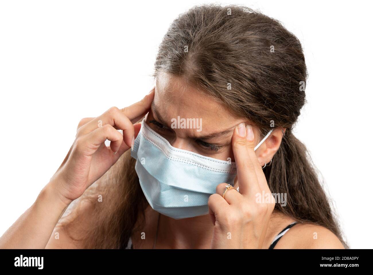 Hurting adult female model touching temples forehead as headache migraine gesture wearing surgical or medical mask as cold flu covid19 symptom concept Stock Photo