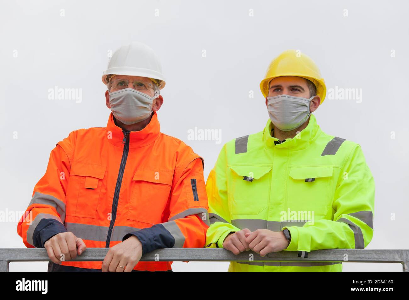 Two workers or engineers with face mask standing on a construction site