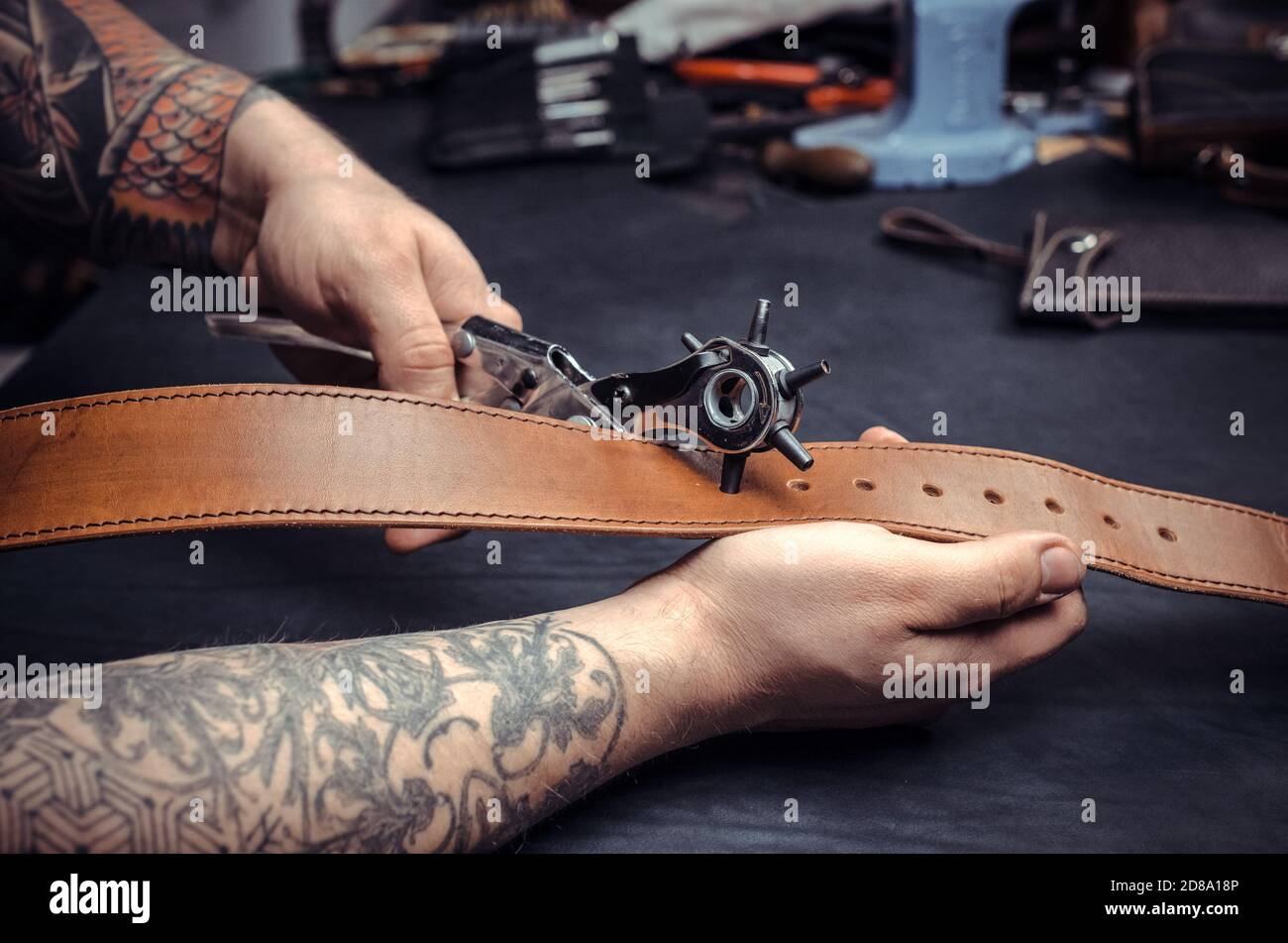 Artisan demostrating leather cutting process at his work area Stock Photo