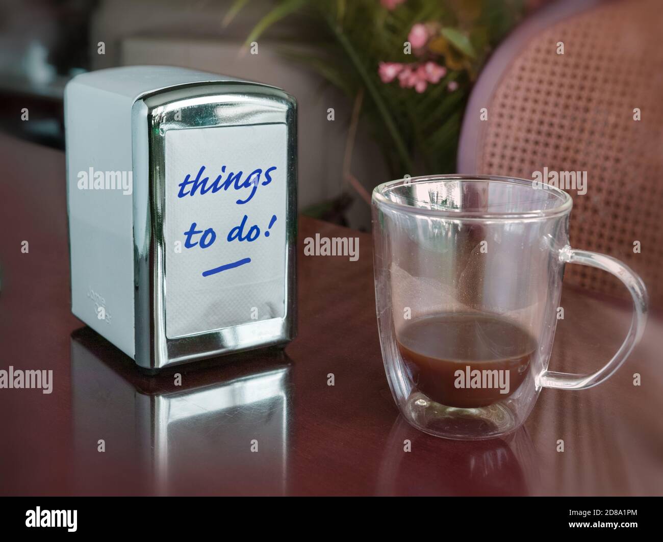 An almost empty cup of coffee and a napkin dispenser that reminds him or her that things must be done (today?). Stock Photo