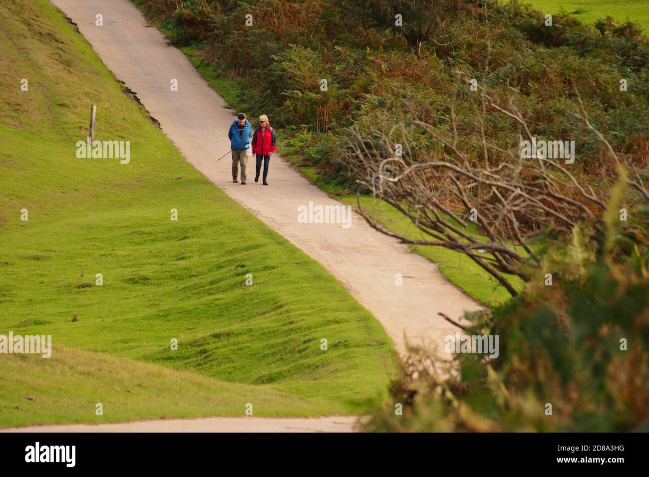 A retired couple enjoying a countryside walk, passing through a golf course on a sunny autumn day Stock Photo