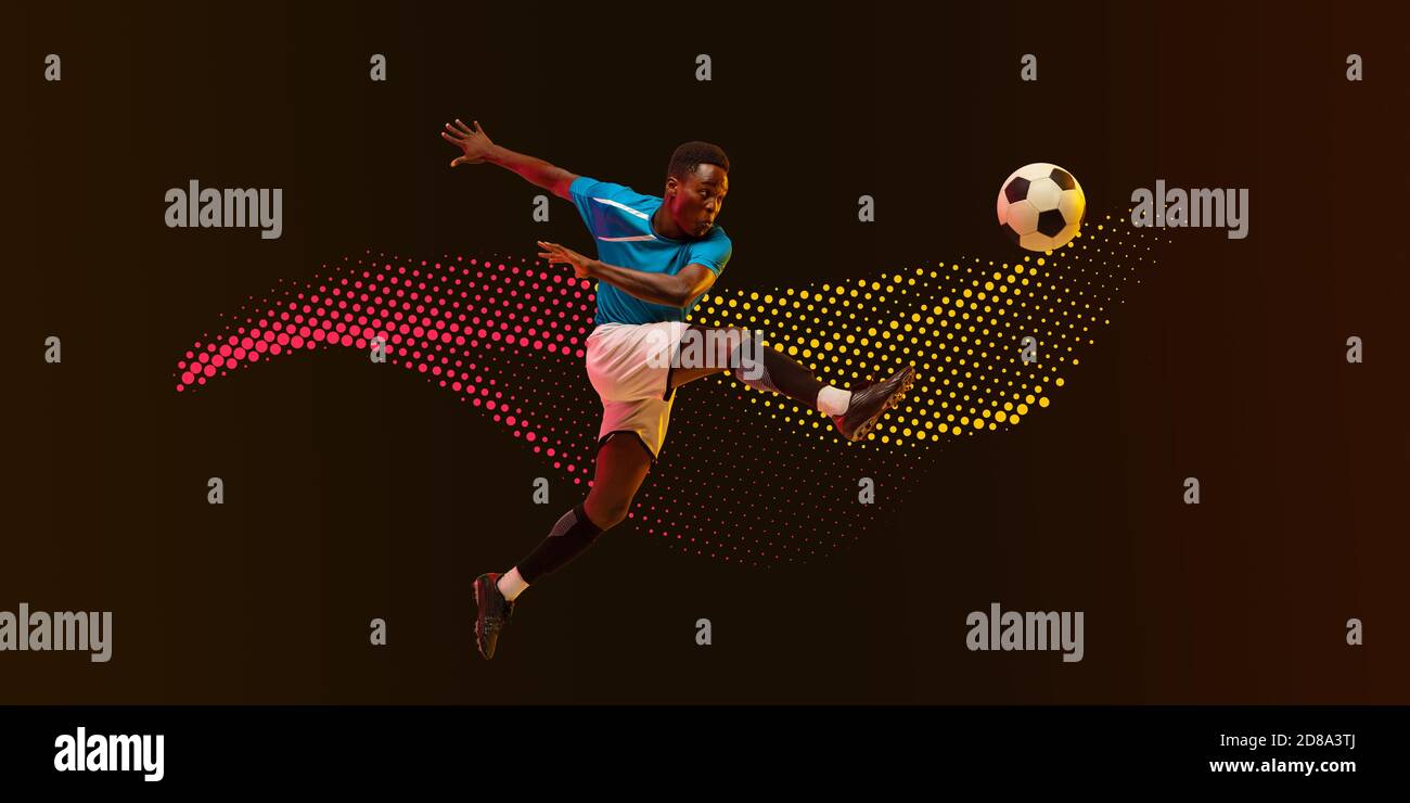 High jumping. Male soccer, football player training in action, kicking in jump isolated on dark