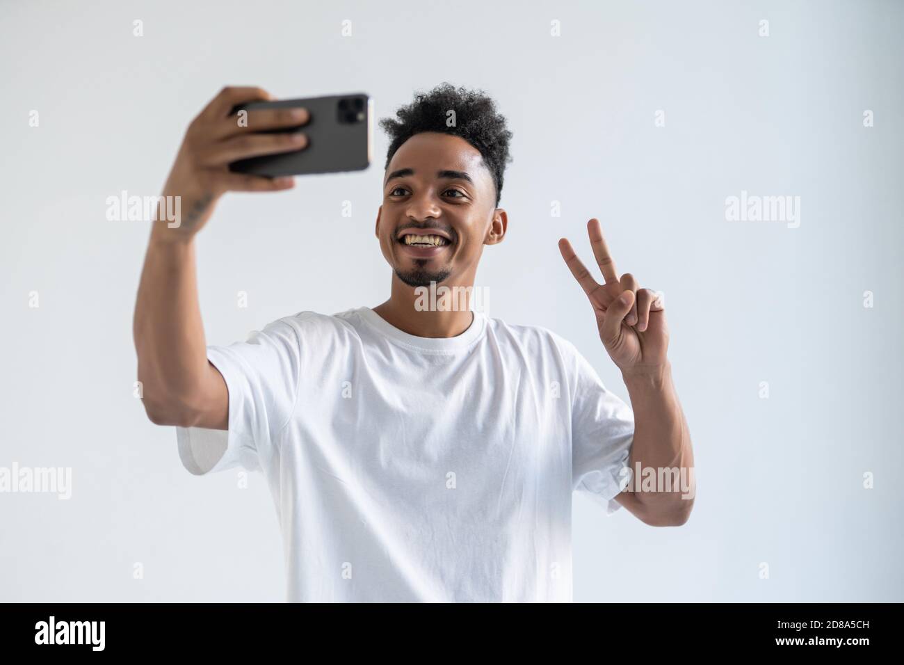 Young african man with peace take selfie on the phone on white backround Stock Photo