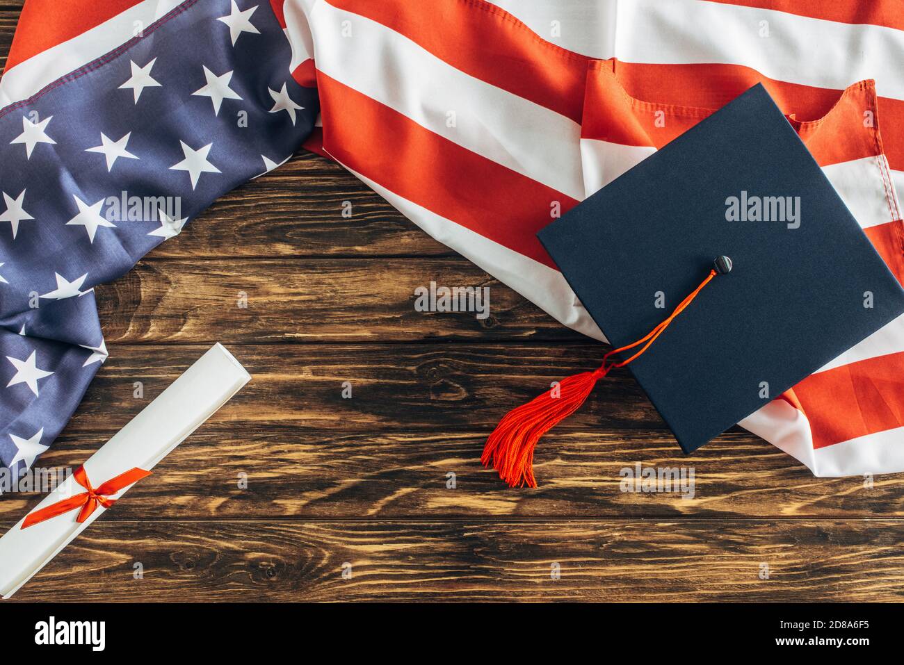 top view of graduation cap and diploma near american flag with stars ...