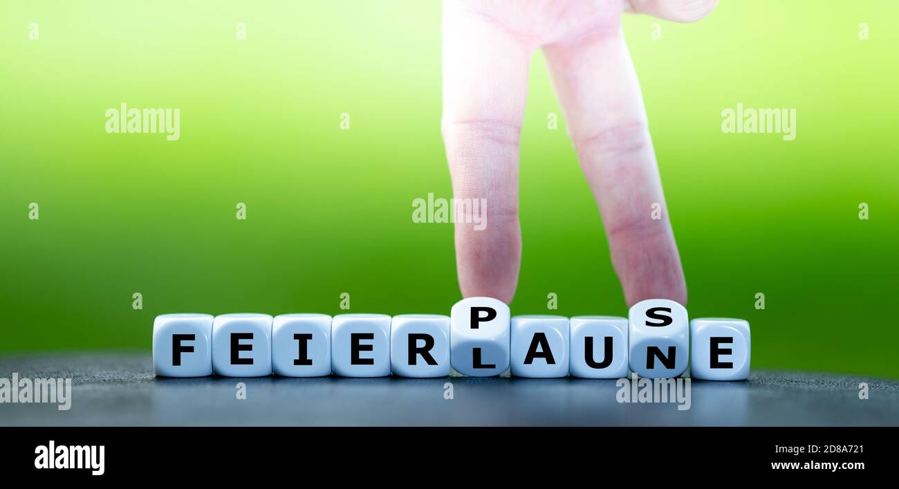 Symbol for not having a party during the corona pandemic. Hand turns dice and changes the German expression 'Feierlaune' (party mood) to 'Feierpause' Stock Photo