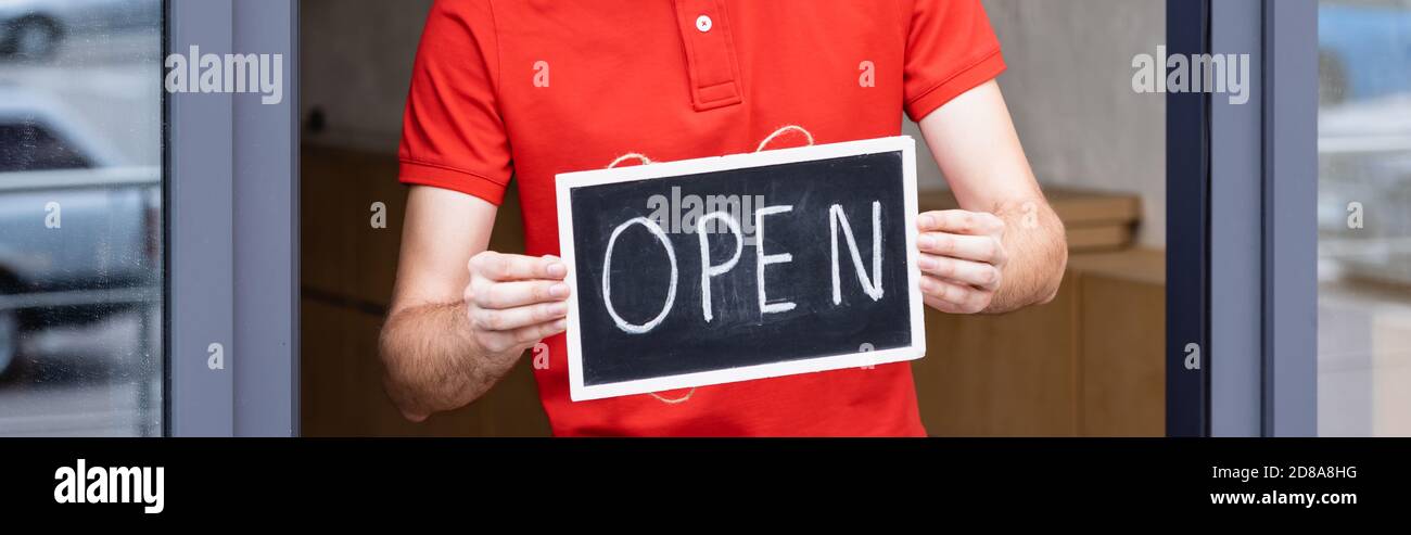 Waiter Lettering Panoramic shot of waiter holding signboard with open lettering near ...