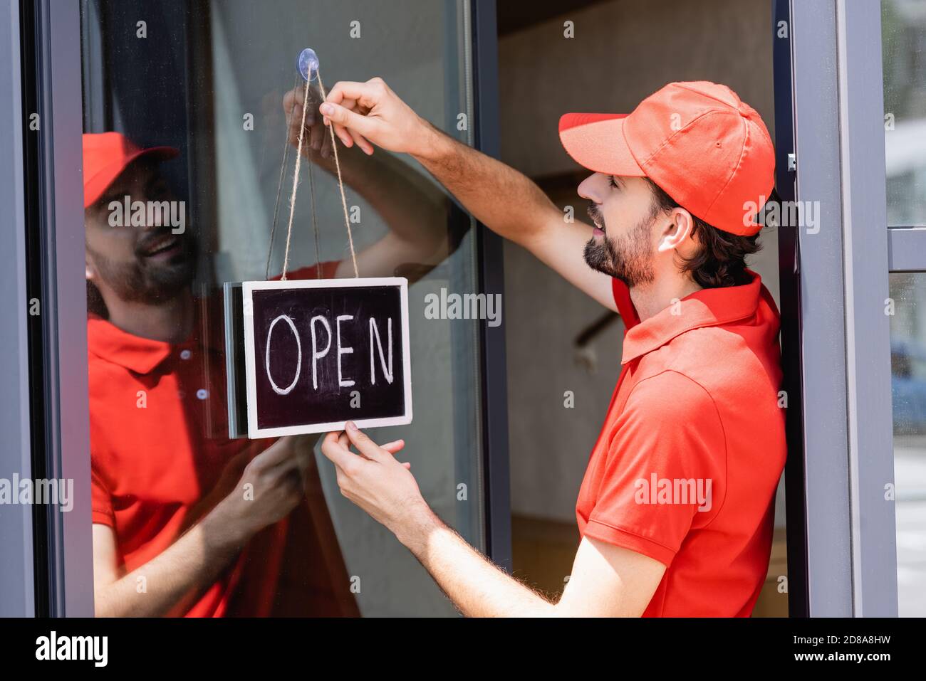 Waiter Lettering Side view of smiling waiter hanging signboard with open lettering on ...