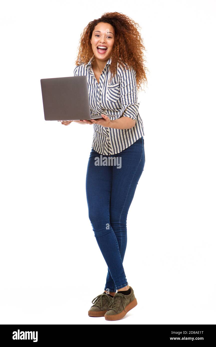 Full length portrait of young woman laughing with laptop computer by isolated white background Stock Photo