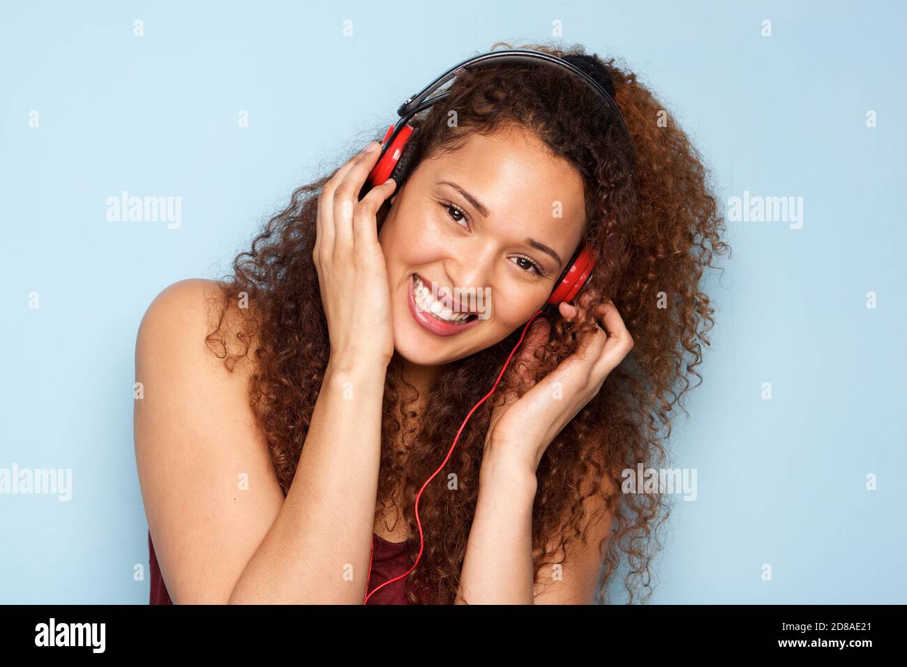Portrait of cheerful young woman listening to music with headphones by ...