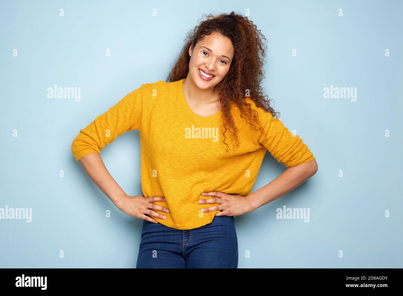 Portrait of attractive young woman with curly hair smiling against gray ...
