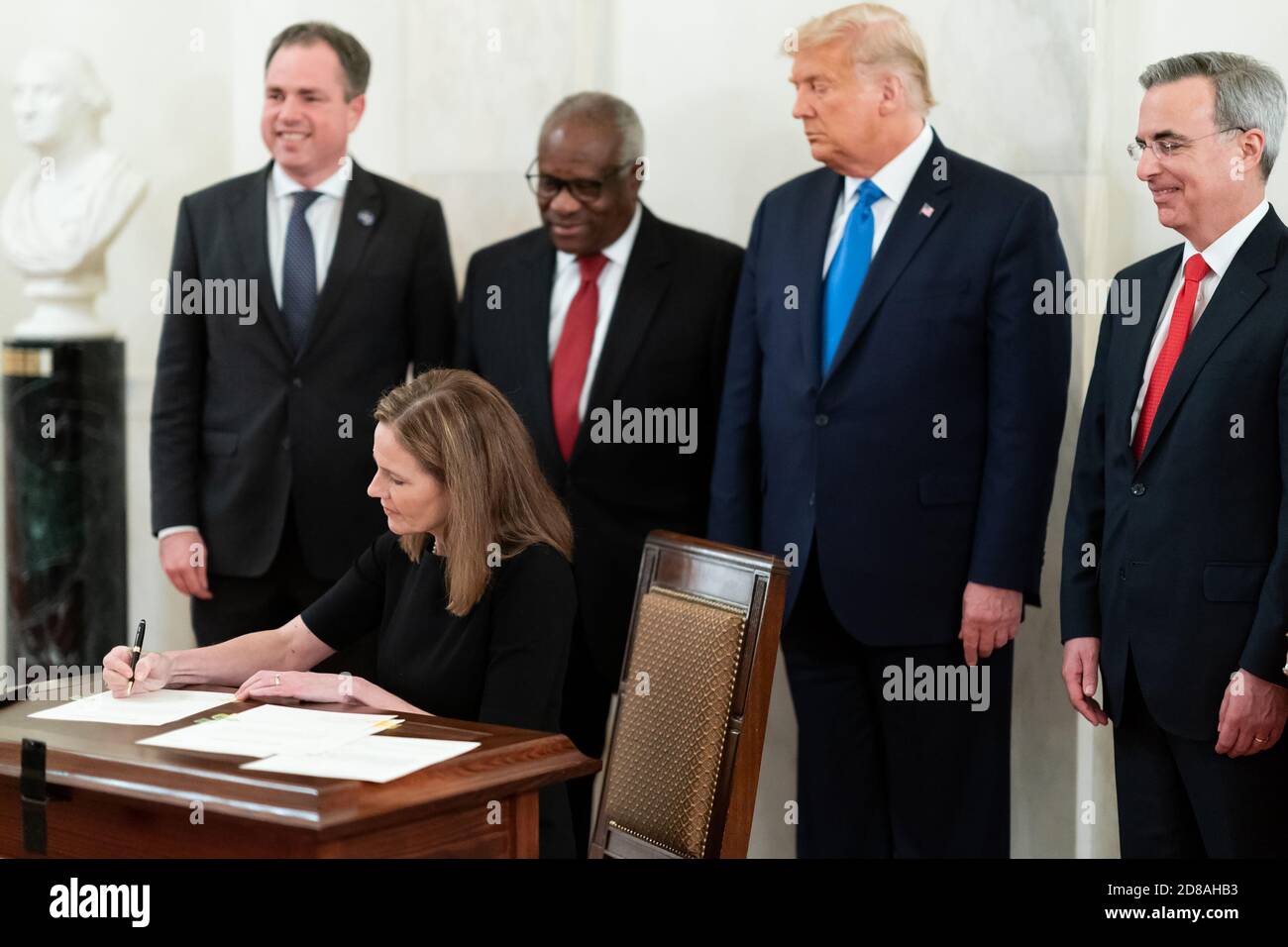 Supreme Court Associate Justice Amy Coney Barrett signs the oath certificate Monday, Oct. 26, 2020, in the Cross Hall of the White House as President Donald J. Trump, Supreme Court Associate Justice Clarence Thomas, White House Counsel Pat Cipollone, and Staff Secretary Derek Lyons observe from behind. (USA) Stock Photo