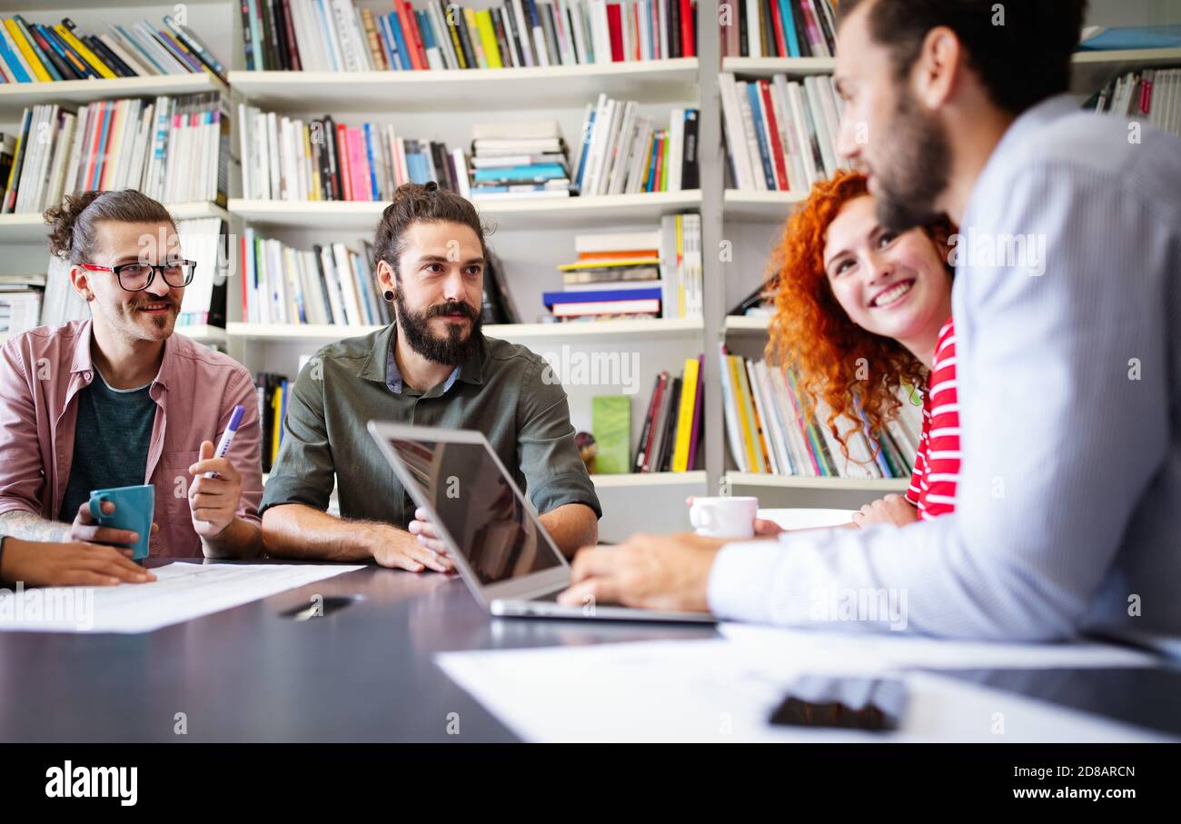 Working together on project. Happy young business colleagues working in ...
