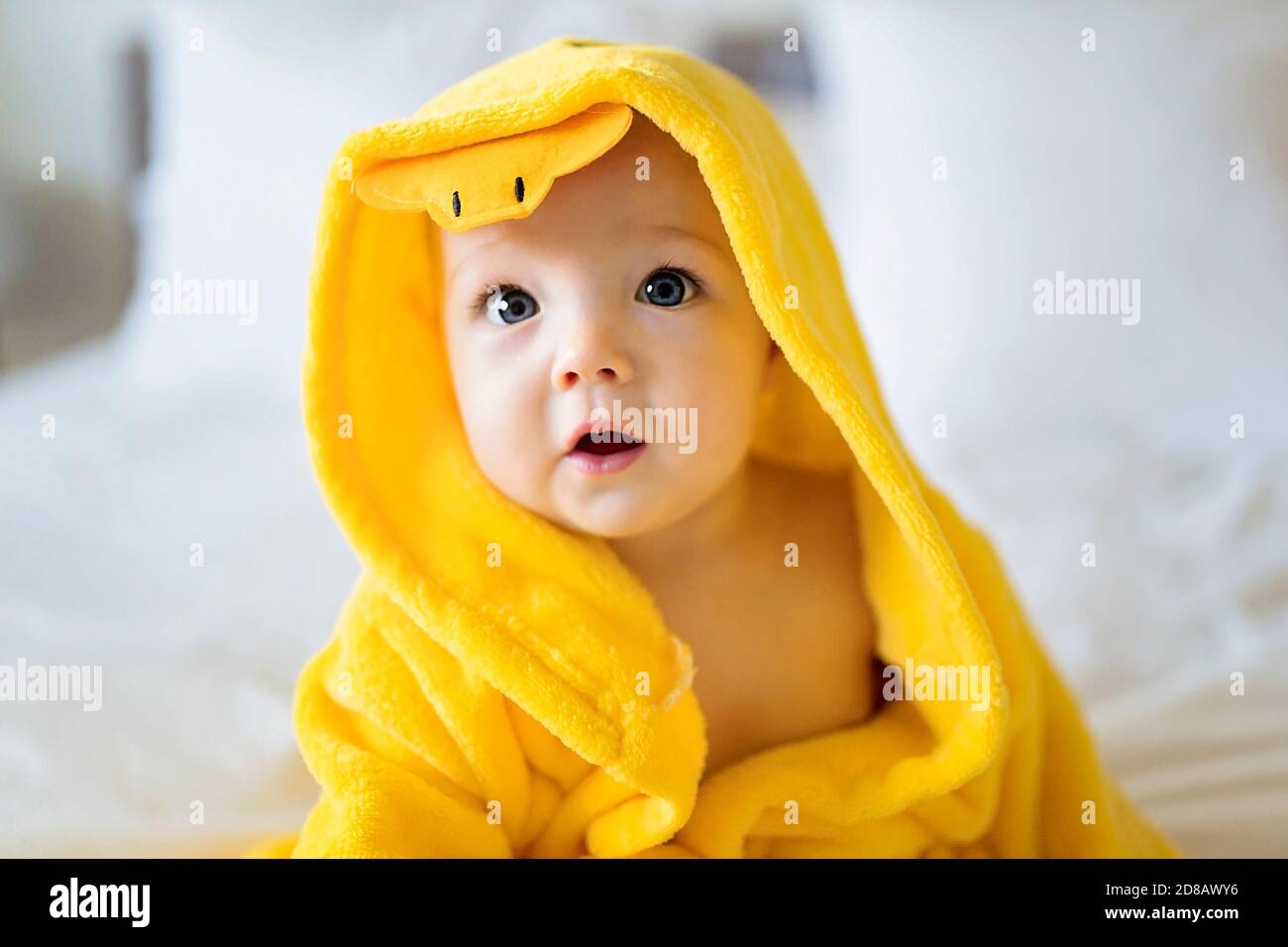 Baby wearing yellow bathrobe duck on parents bed after bath Stock Photo Alamy