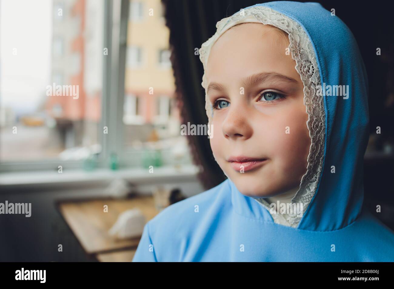 Side portrait of a little Muslim girl wearing a blue hijab. Concept of