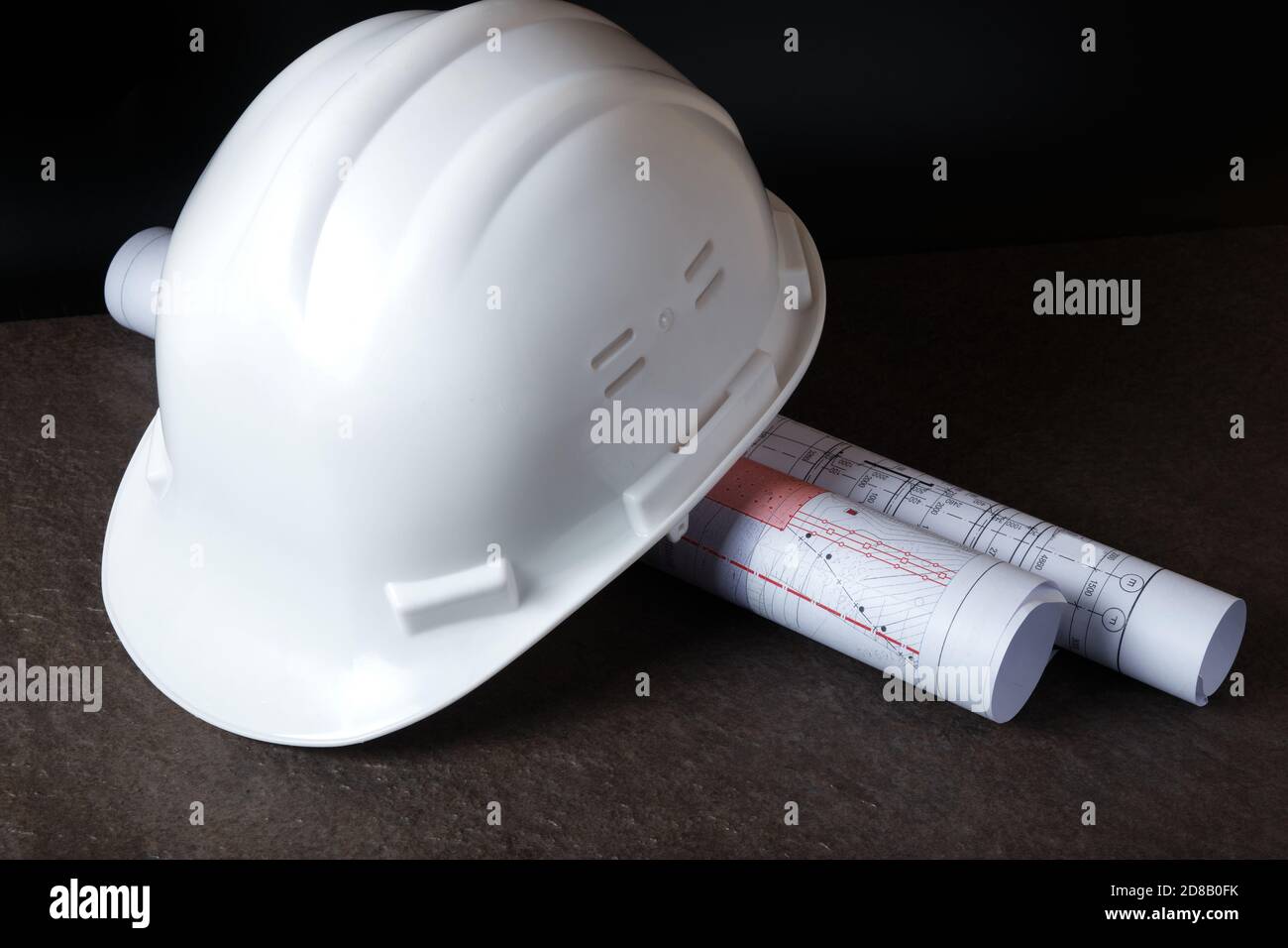 White hardhat and rolled engineering drawings at engineer workplace Stock Photo