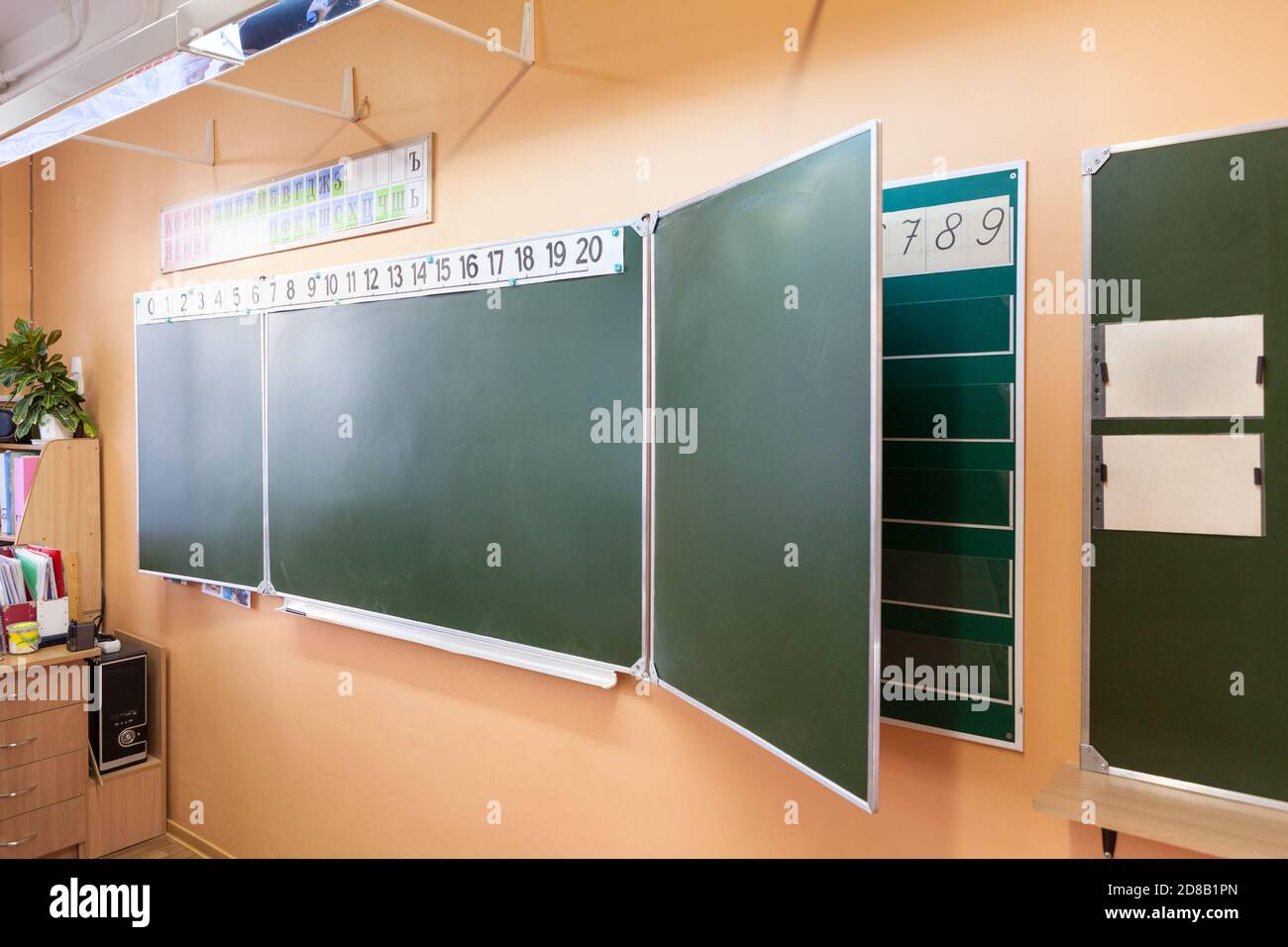 Green blackboard with Russian letters is on the wall in the classroom Stock Photo
