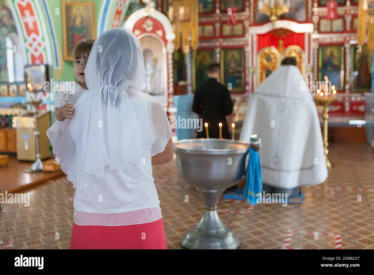 People stand close to baptistery. It is sacrament of initiation into the church. Godmother with