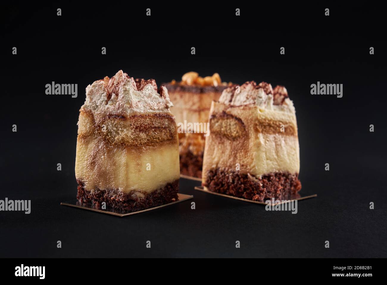 Closeup View Of Three Square Pieces In Row Decorated With Whipped Cream And Cocoa Isolated On Black Tiramisu Cake With Three Layers Of Chocolate Biscuit And Coffee Syrup With Cognac And Cream Closeup View Of Three Square Pieces In Row Decorated With Whipped Cream And Cocoa Isolated On Black Tiramisu Cake With Three Layers Of Chocolate Biscuit And Coffee Syrup With Cognac And Cream
