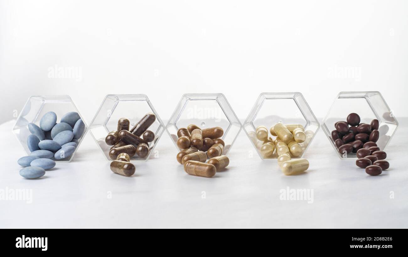 Variety of medical capsules and tablets spilled out of a glass ...