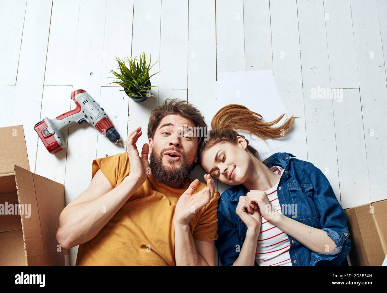Moving to an apartment a man and a woman lie on the floor and a flower