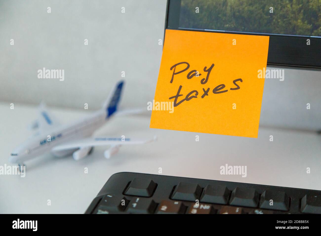 Reminder pay taxes sticked on monitor at freelancer's workplace Stock Photo