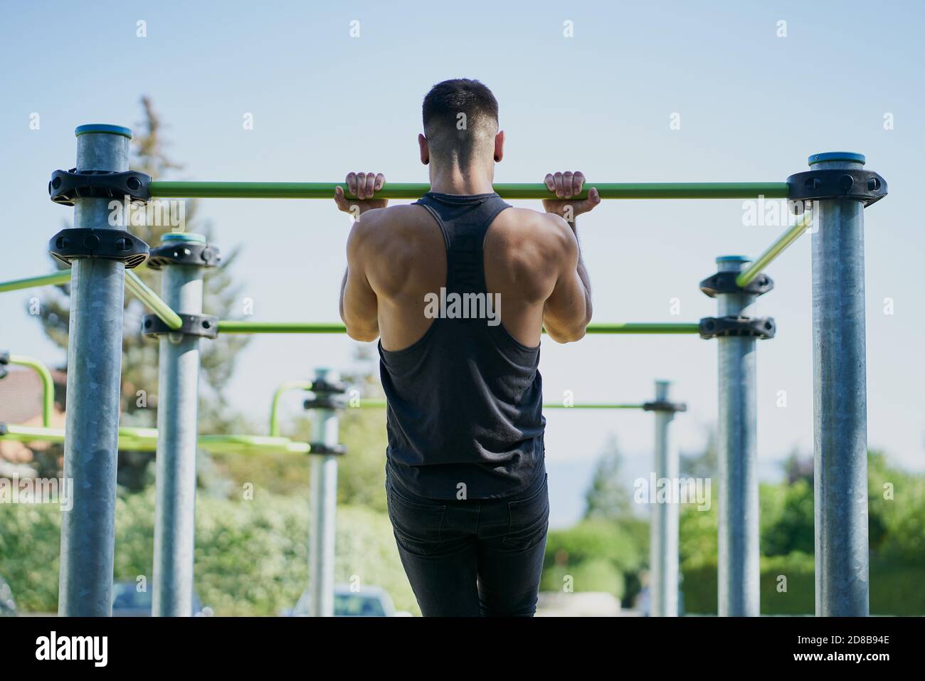 Back view of a man practicing calisthenics in a park on sunny day Stock Photo