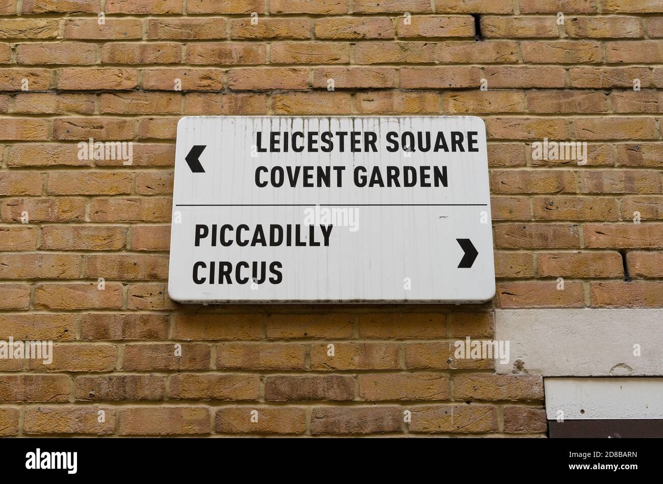 Leicester Square and Piccadilly Circus direction sign against a brick